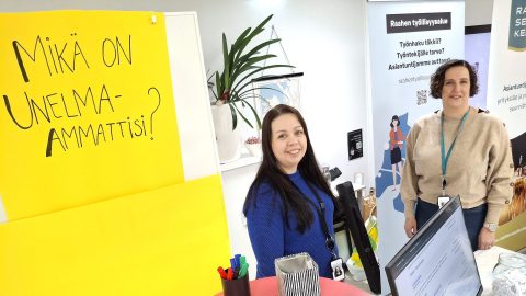 TE-asiantuntijoita messupöydän takana. Vasemmalla lukee keltaisella pahvilla "Mikä on unelma-ammattisi?".